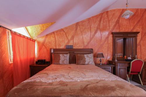 - une chambre avec un lit et une couette en orange dans l'établissement Chambre familiale, à Aït Mouloud