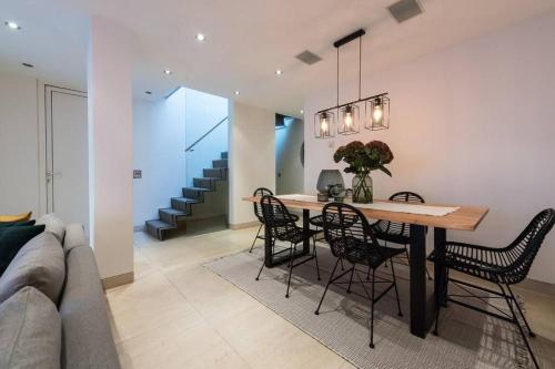 uma sala de jantar e sala de estar com mesa e cadeiras em Spectacular Mews House in Holland Park em Londres