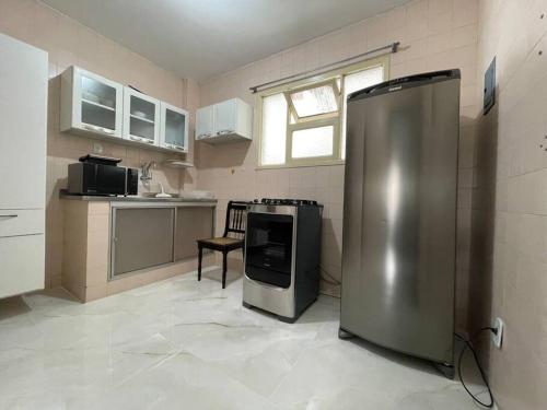 eine Küche mit einem Kühlschrank und einem Stuhl darin in der Unterkunft Quarto e sala 100 mts da praia in Guarapari