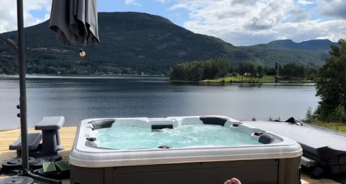 bañera de hidromasaje en una terraza con vistas al lago en Lakefront Villa, exclusive leisure property near Vrådal Golf, Straand Summerland & Panorama Ski center, en Vradal