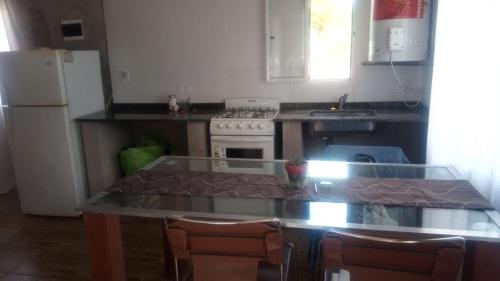 uma cozinha com uma mesa com cadeiras e um frigorífico em Arriba y La escondida em Villa Gesell