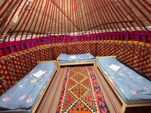 dwa łóżka w dużym namiocie z dywanem w obiekcie Jaichy Yurt Camp w mieście Këk-Say