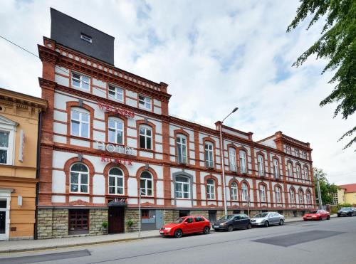 a large brick building with cars parked in front of it at Hotel RICHTR in Frýdek-Místek