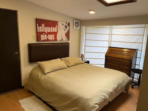 Schlafzimmer mit einem Bett, einer Kommode und einem Poster in der Unterkunft Cozy Room in La Paz