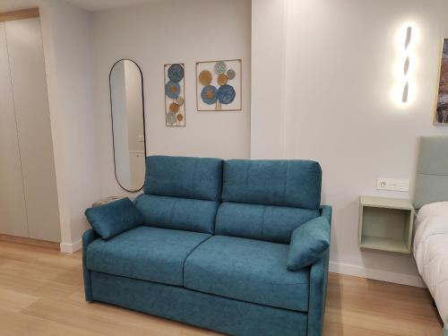 a blue couch in a room with a bed at Apartamentos Centro Oviedo Caveda in Oviedo