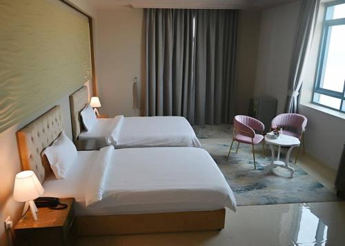 Bareen Hotel في عجمان: غرفة فندقية بسريرين وطاولة وكراسي