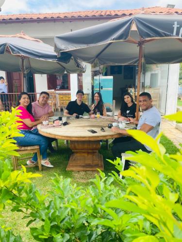 a group of people sitting around a table under an umbrella at POUSADA CHARLOTTE in Tiradentes
