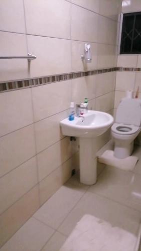 a white bathroom with a toilet and a sink at Duvas Home in Umlazi