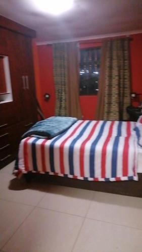 a bed with a striped blanket in a room at Duvas Home in Umlazi