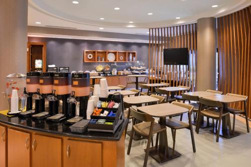 Un restaurante con mesas y sillas y un mostrador con botellas de vino. en SpringHill Suites by Marriott Corona Riverside, en Corona