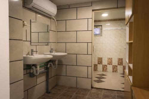 uma casa de banho com 2 lavatórios e um chuveiro em Sneza em Podgorica
