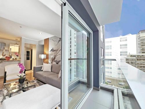a living room with a couch and a large window at Skyliving Towers Apartments - Perú in Lima