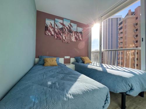 a bedroom with two beds and a large window at Karola cosy in Benidorm