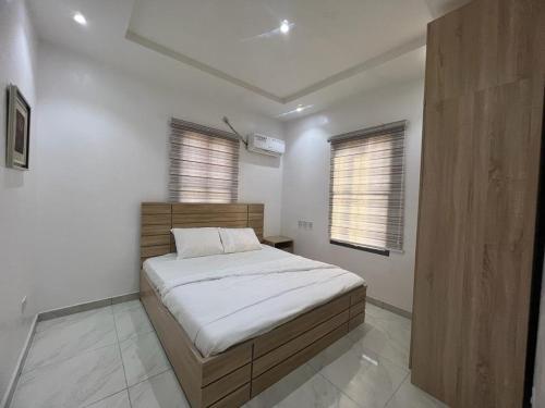 a bedroom with a bed and two windows at Oluyole Apartments Ibadan in Ibadan
