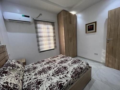 Schlafzimmer mit einem Bett mit einer schwarzen und weißen Bettdecke in der Unterkunft Oluyole Apartments Ibadan in Ibadan
