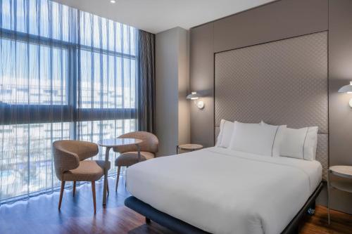 ロスピタレート・デ・リョブレガートにあるAC Hotel Som by Marriottのベッド、テーブル、椅子が備わるホテルルームです。