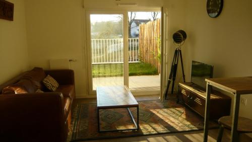 uma sala de estar com um sofá e uma mesa de vidro em Appartement, terrasse et jardin à 2 pas de Paris em Noisy-le-Sec