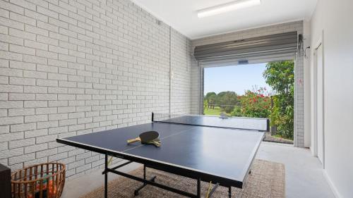 a ping pong table in a room with a brick wall at Adelong in Kiama Downs