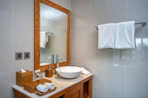 a bathroom with a bowl sink and a mirror at Paon Desa Ubud in Ubud