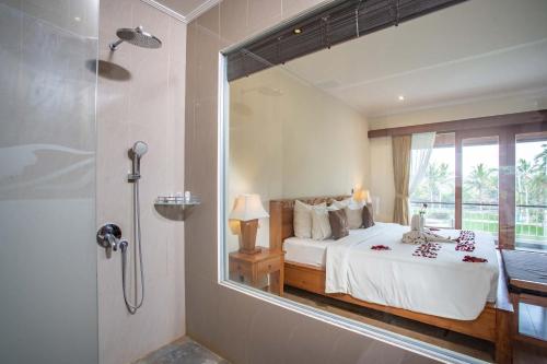 a bedroom with a bed and a shower with a mirror at Paon Desa Ubud in Ubud