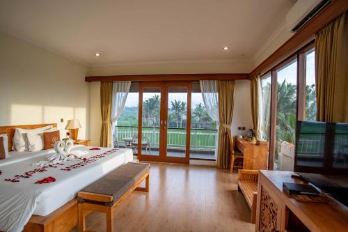 a bedroom with a large bed and a large window at Paon Desa Ubud in Ubud
