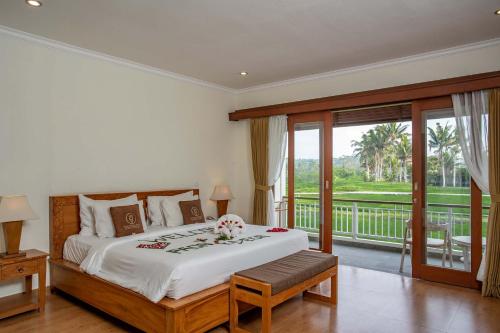 a bedroom with a large bed and a balcony at Paon Desa Ubud in Ubud