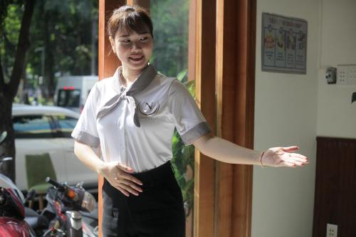 a woman standing in a doorway with her arm outstretched at Lantern Hotel in Ho Chi Minh City