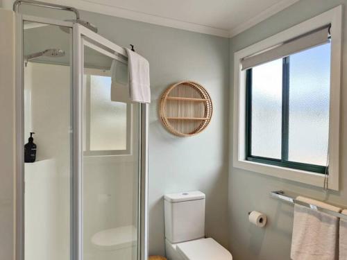 ein Bad mit einer Dusche, einem WC und einem Fenster in der Unterkunft Unit 3 Little Banksia - A Perfect Base in Bicheno