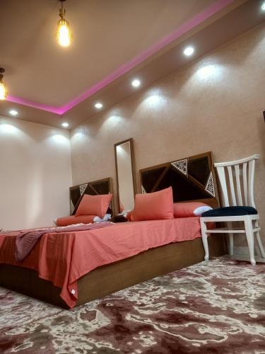 A 5-star hotel room in front of Mansoura University في المنصورة: غرفة نوم بسرير كبير مع شراشف حمراء وكرسي