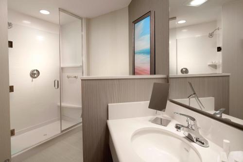 a bathroom with a sink and a mirror and a shower at Courtyard by Marriott Palm Beach Jupiter in Jupiter
