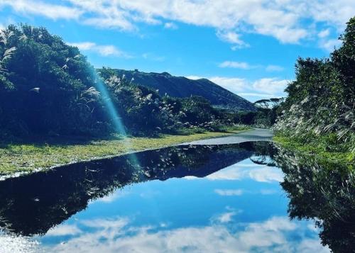 a river with a reflection of a rainbow in the water at 三浜館 伊豆大島 in Oshima
