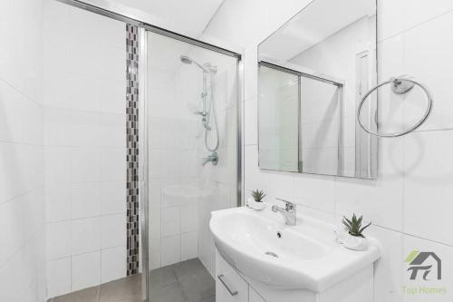 a white bathroom with a sink and a shower at Entire Home in Lidcombe in Sydney