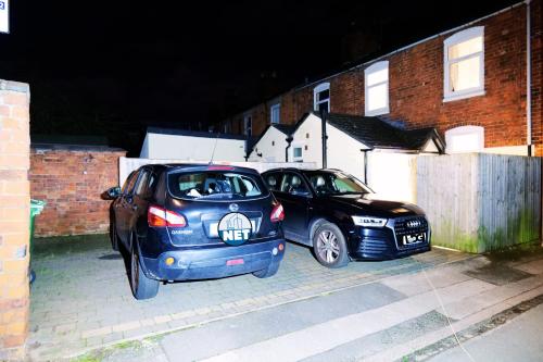 two cars parked in a parking lot at night at Town Centre House with parking, Wi-Fi in Stafford