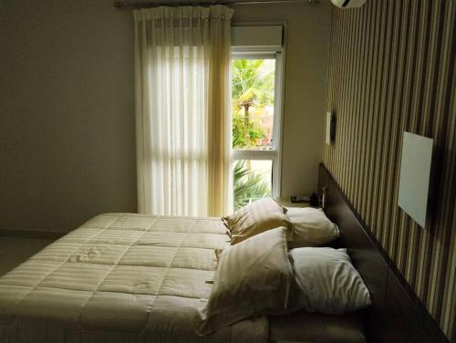 a bedroom with a large bed and a window at Casa alto padrão, Jd. Acapulco in Guarujá