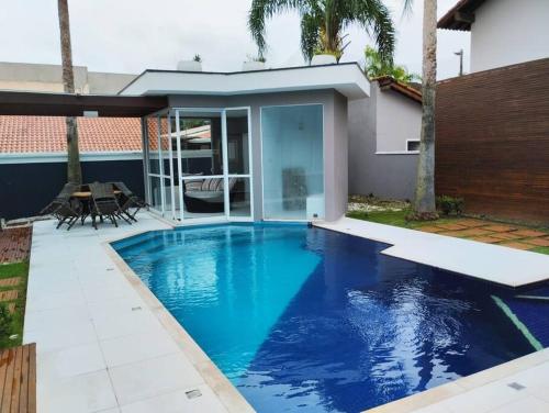 a blue swimming pool in a backyard with a house at Casa alto padrão, Jd. Acapulco in Guarujá