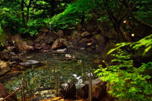 una corriente de agua con rocas y árboles en Mercure Urabandai Resort & Spa, en Kitashiobara