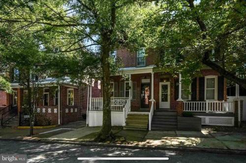 een rood bakstenen huis met een witte veranda en een trap bij House of the Heart at Trolley Square! in Wilmington