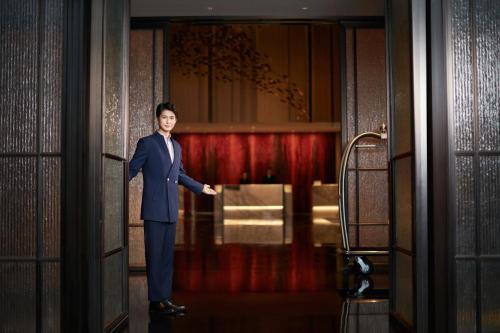 a man in a suit standing in a doorway at HUALUXE Yangjiang City Center in Yangjiang