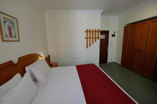 a bedroom with a bed with white sheets and a red blanket at City Inn Palace Hotel in Ramallah
