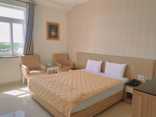 a bedroom with a bed and a chair and a window at Thuan Phat House Soc Trang in Soc Trang