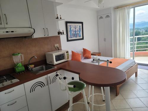 a kitchen with a table and a microwave and a bed at Arco Iris Atacames in Atacames