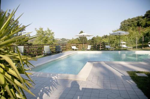 a swimming pool with chairs and umbrellas next to it at Country House Angelo Blù in Urbania