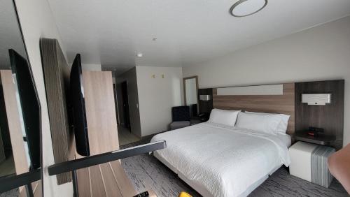 a hotel room with a bed and a flat screen tv at Holiday Inn Express Portland SE - Clackamas Area by IHG in Gladstone