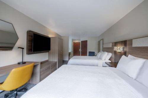 a hotel room with two beds and a flat screen tv at Holiday Inn Express Portland SE - Clackamas Area by IHG in Gladstone