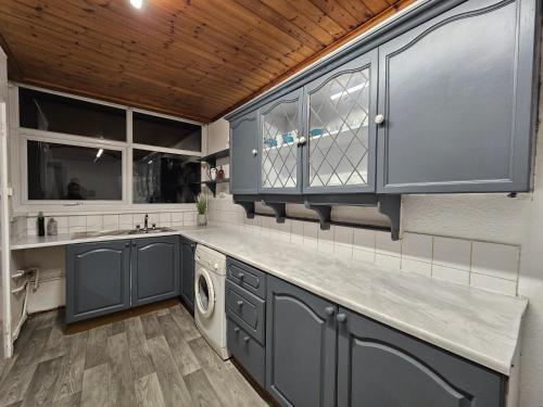 a kitchen with blue cabinets and a washing machine at Spitalfields Rooms in London