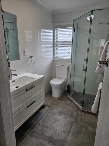 a bathroom with a toilet and a glass shower at Redwood Apartments in Rotorua