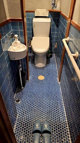 ein Bad mit WC und ein Paar Schuhe auf dem Boden in der Unterkunft おもや彩OmoyaSai-天然温泉付き貸別荘1棟貸し in Kirishima