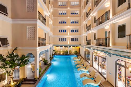 een binnenzwembad in een gebouw met een zwembad bij Amina Lantana Hoi An Hotel & Spa in Hội An