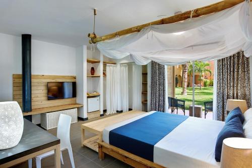 a bedroom with a bed and a table and a tv at Veranda Pointe Aux Biches Hotel & Spa in Trou aux Biches