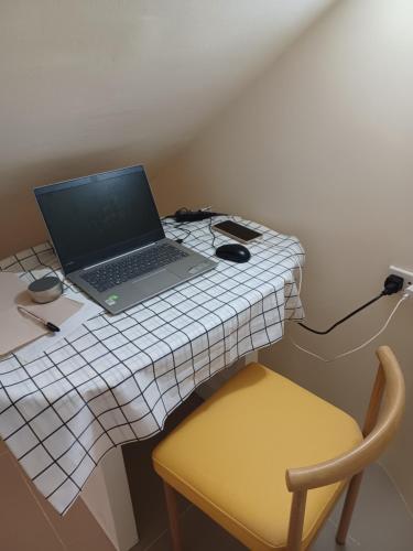 a laptop computer sitting on a table with a yellow chair at Cebu City Unit1 Spacious 2BR near SM Seaside NuStar Ocean Park Dynamic Herb Anjo in San Roque